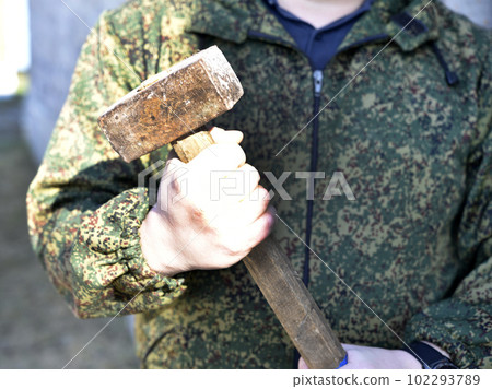 A sledgehammer in the hands of a man. A large hammer in his hands. 102293789