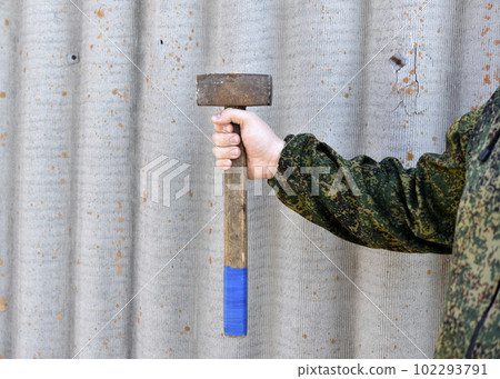 A sledgehammer in the hands of a man. A large hammer in his hands. 102293791