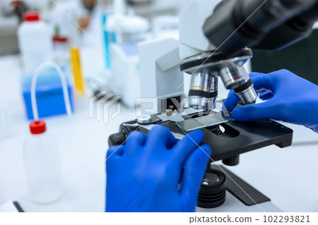 Unrecognizable doctor scientist working in modern laboratory with microscope, genetic researching. 102293821