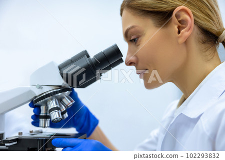 Scientist woman working with lab researching, analyzing microscope slides 102293832