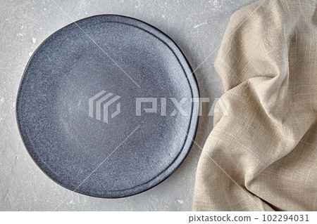 An empty gray ceramic plate and a rough linen napkin on a gray concrete table. Background for displaying food 102294031