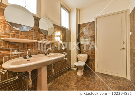 a bathroom with brown tiles on the walls and wood flooring around the bathtub, sink, and mirror 102294555