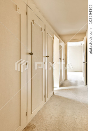 an empty room with white walls and beige carpeting, there is no one person in the room to be seen 102294563