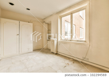 an empty room with white cupboards and cabinets in the corner, looking out onto the street from the window an empty room with white cupboards and cabinets in the corner, looking out onto the street from the window 102294569