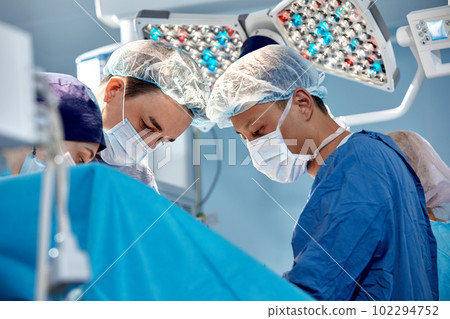Group of surgeons doing surgery in hospital operating theater, international medical team doing critical operation Group of surgeons doing surgery in hospital operating theater, international medical team doing critical operation 102294752