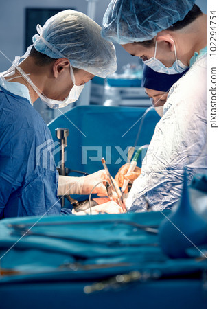 The team of surgeons in the operating room bent over the patient, complex surgical operation, high-tech medicine, life saving 102294754