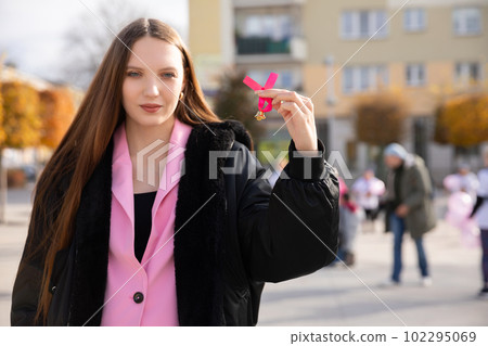 A young woman holds a pink ribbon during a march for preventive breast examinations. 102295069
