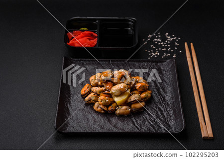 Delicious marinated mussels with spices and herbs on a ceramic plate 102295203