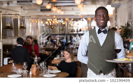 Portrait of male waiter who is holding tray with order 102299409