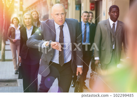 Stressed businessman checking time and running Stressed businessman checking time and running 102299485