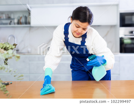Female cleaning service worker wiping furniture in office kitchen 102299497