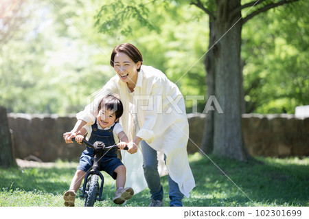 Parent and child practicing bicycles Mom and son in a fresh green park Parent and child practicing bicycles Mom and son in a fresh green park 102301699