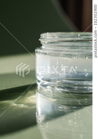 Transparent gel in a jar on a green background. Transparent gel in a jar on a green background. 102302900