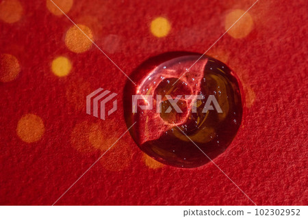 A drop of serum on a red background with bokeh. A drop of serum on a red background with bokeh. 102302952