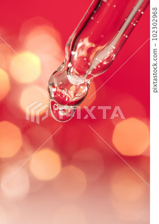 Pipette with serum on a red holiday background with bokeh. Pipette with serum on a red holiday background with bokeh. 102302968