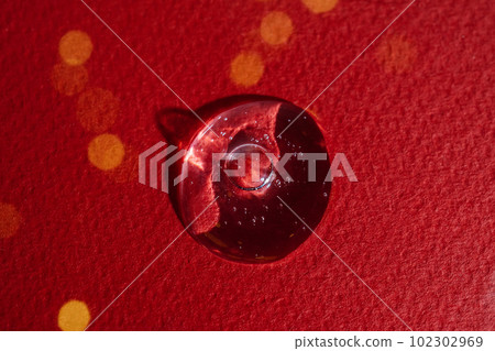 A drop of serum on a red background with bokeh. A drop of serum on a red background with bokeh. 102302969