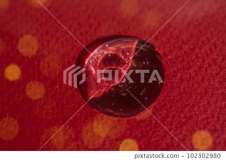A drop of serum on a red background with bokeh. 102302980
