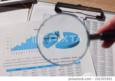 Woman looks at statistics paper through magnifier glass 102303981