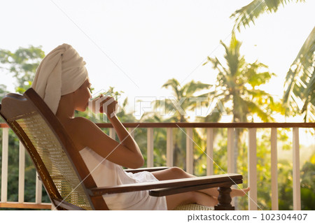 Woman With a Cup of Coffee After Shower on Open Resort Balcony Against Nature Background 102304407