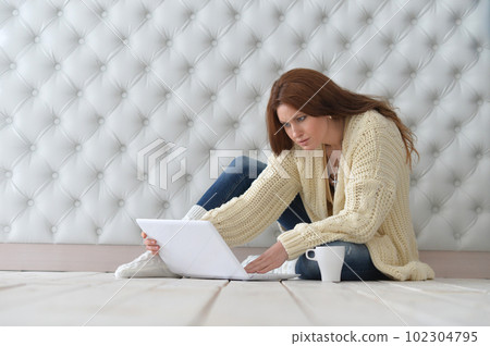 Beautiful woman with laptop sitting on floor and drinking coffee 102304795