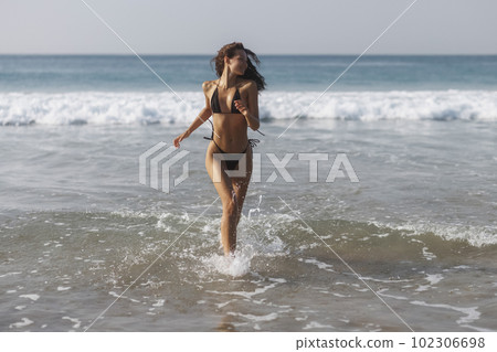 Happy bikini beach vacation woman running to ocean splashing water in freedom feeling. Happiness carefree lifestyle banner with blue ocean copy space 102306698