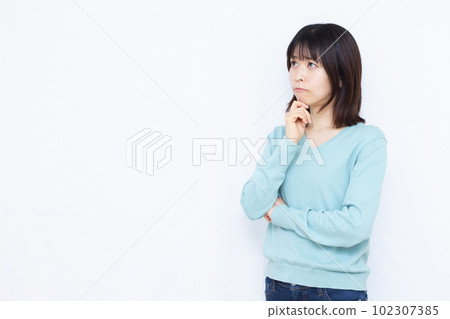 A woman in her thirties who is seriously worried in front of a white background 102307385