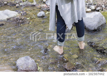 Middle female feet doing earthing in the river 102307442