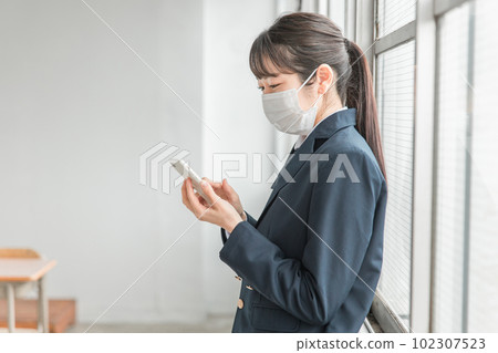 High school students and high school girls wearing masks using smartphones in the classroom High school students and high school girls wearing masks using smartphones in the classroom 102307523
