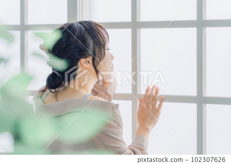 Profile of an Asian woman looking out the window Profile of an Asian woman looking out the window 102307626