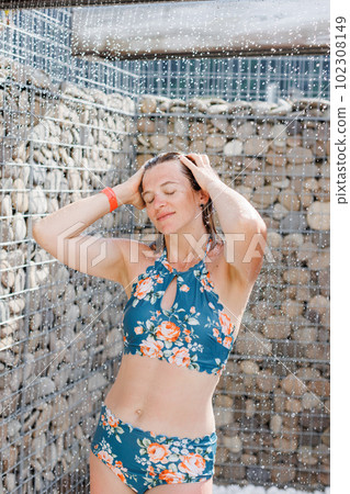 Beautiful woman, wearing swimsuit, taking shower in outdoor in her summer holidays Beautiful woman, wearing swimsuit, taking shower in outdoor in her summer holidays 102308149