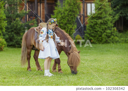 young girl in Ukrainian national dress strokes a pony 102308342