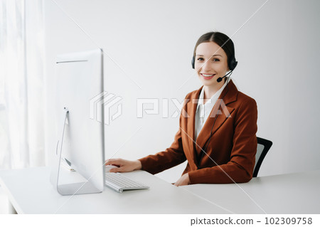 Serious call center operator in wireless headset talking with customer, woman in headphones with microphone consulting client on phone in customer support service in office center.. 102309758
