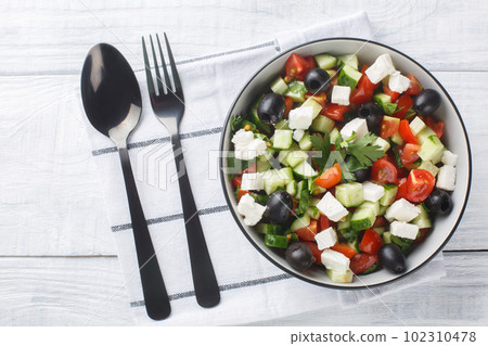 Coban Salatasi or Shepherds Salad is a simple yet delicious side dish made with tomato, cucumber, peppers, onion, herbs and cheese closeup in the bowl. Horizontal top view 102310478