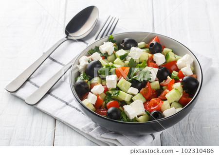 Coban Salatasi or Shepherds Salad is a simple yet delicious side dish made with tomato, cucumber, peppers, onion, herbs and cheese closeup in the bowl. Horizontal 102310486