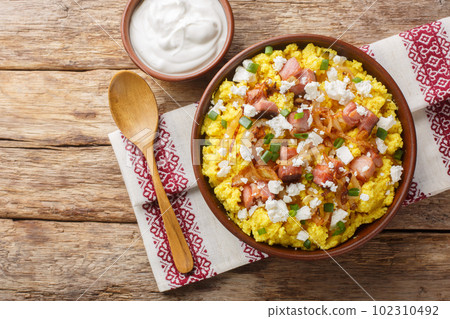 Ukrainian cuisine maize porridge with onion, cracklings and cheese closeup on the bowl. Horizontal top view 102310492