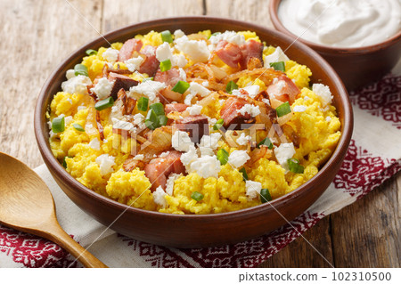 Corn porridge served with cheese, fried onion and bacon closeup on the bowl. Horizontal 102310500