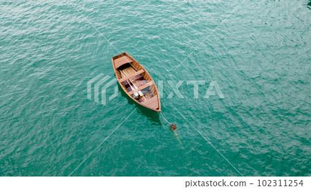 A stunning view of a wooden boat on the lake surrounded by the lush green landscape from a top view perspective. 102311254
