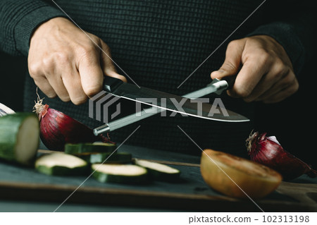 man steels a kitchen knife man steels a kitchen knife 102313198
