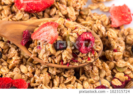 Muesli oat cereals close up background with dry fruits in wooden spoon 102315724