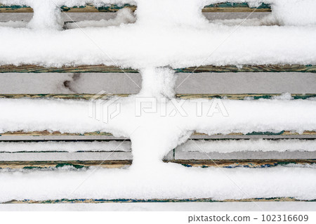 above view of snow-covered planks of wooden bench above view of snow-covered planks of wooden bench 102316609