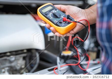 Asian auto mechanic check for repair under the hood of broken down car on the side of the road. 102316712