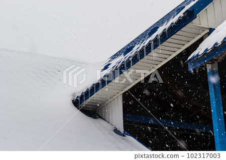 Snow on the roof of a red, brown metal tile of a European house Snow on the roof of a red, brown metal tile of a European house 102317003