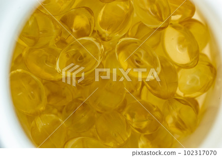 lots of yellow gelatin capsules on a light background. omega viramins, close-up, macro 102317070
