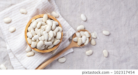 White beans in wooden bowl with spoon on linen tablecloth background White beans in wooden bowl with spoon on linen tablecloth background 102317454