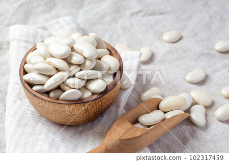 White beans in wood bowl with scoop on linen cloth background with copy space White beans in wood bowl with scoop on linen cloth background with copy space 102317459