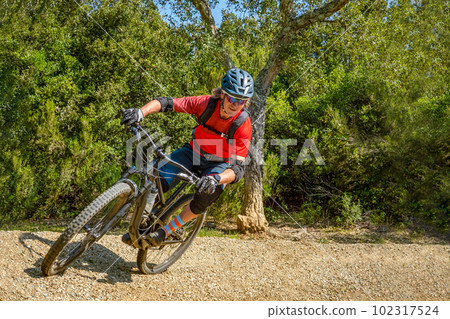 Mountain biker takes a turn at an angle and in a professional position. Sporty and dynamic image that reproduces enduro mountain biking Mountain biker takes a turn at an angle and in a professional position. Sporty and dynamic image that reproduces enduro mountain biking 102317524