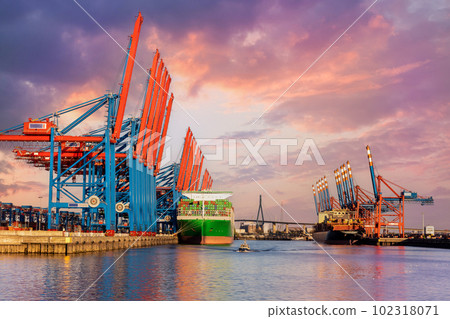 Scenic front giant cargo container ship loading Hamburg city port harbour seaport cranes warm dramatic sky evening sunset light. Global commercial trade freight charter shipping logistics background Scenic front giant cargo container ship loading Hamburg city port harbour seaport cranes warm dramatic sky evening sunset light. Global commercial trade freight charter shipping logistics background 102318071