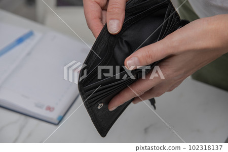Close-up young European woman holding open empty black leather wallet. without cash. financial problems Close-up young European woman holding open empty black leather wallet. without cash. financial problems 102318137