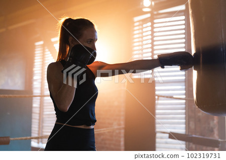 Women self defense girl power. Strong woman fighter training punches on boxing ring. Healthy strong girl punching boxing bag. Training day in boxing gym. Strength fit body workout training Women self defense girl power. Strong woman fighter training punches on boxing ring. Healthy strong girl punching boxing bag. Training day in boxing gym. Strength fit body workout training 102319731