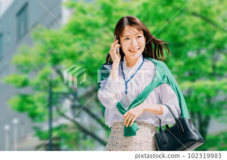 年輕的日本女商人邊走邊用智能手機聊天 102319983